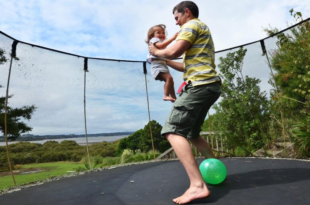 dad and daughter jumping on a trampoline