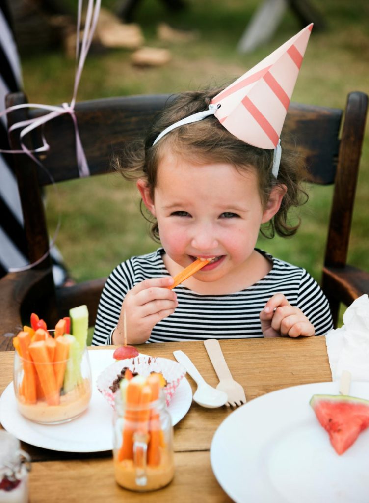 girl at birthday party eating carrots and hummus