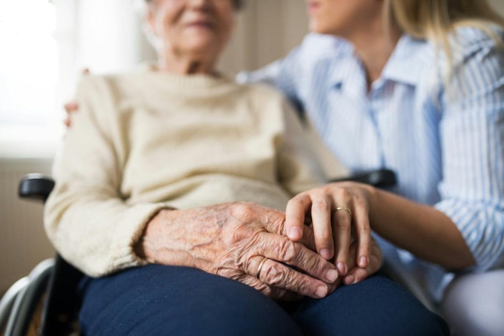 adult woman holding elderly woman's hand