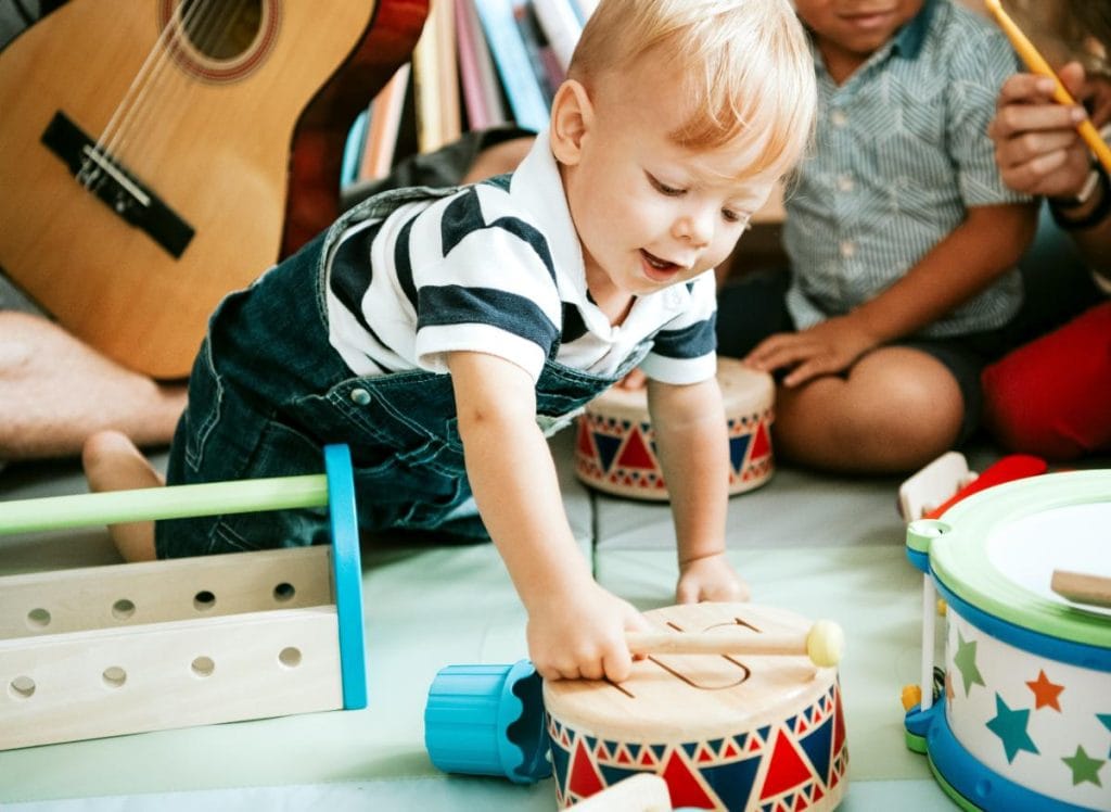 toddler boy playing with wooden drums