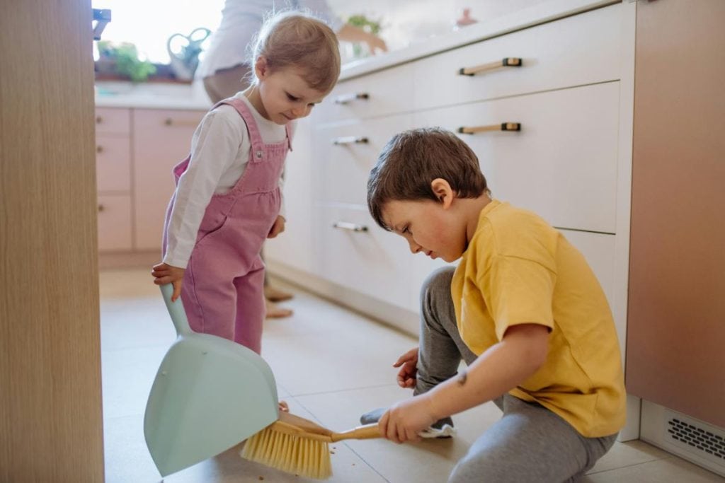 two young kids sweeping kitchen floor