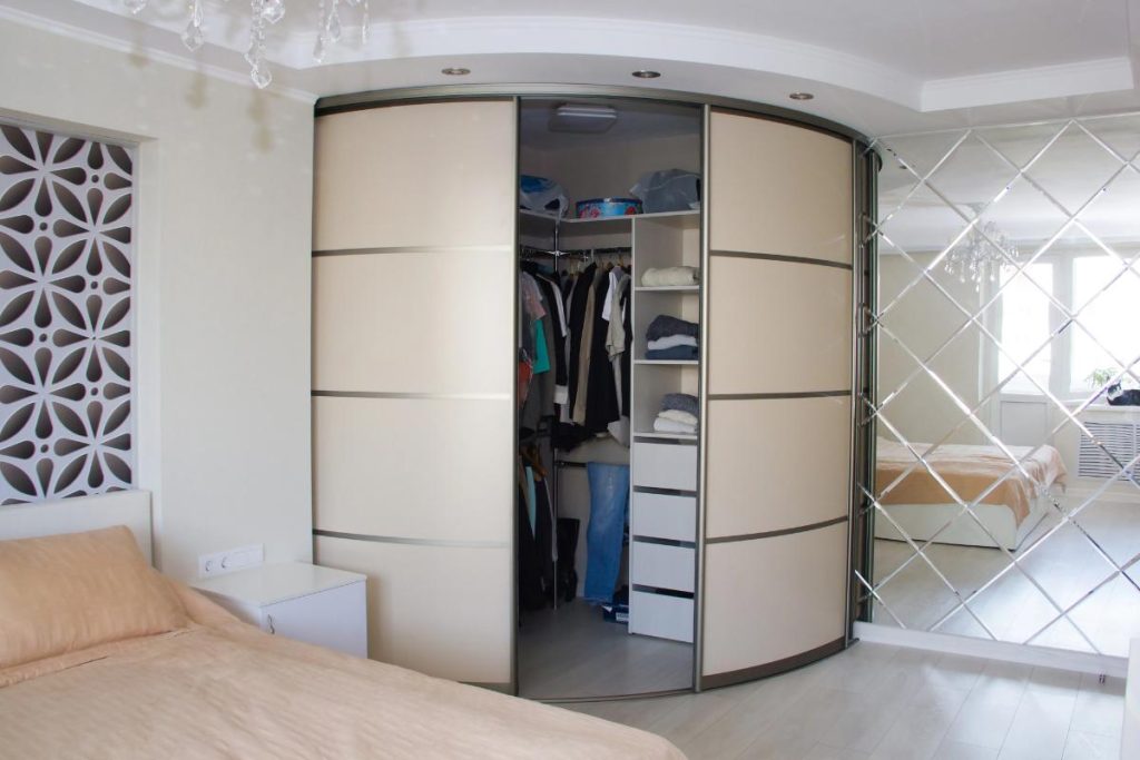 a bedroom with a large wardrobe with curved doors