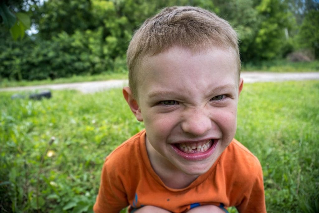 grinning boy with missing tooth playing outdoors