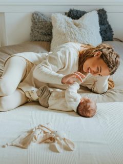 mom laying on bed looking at baby