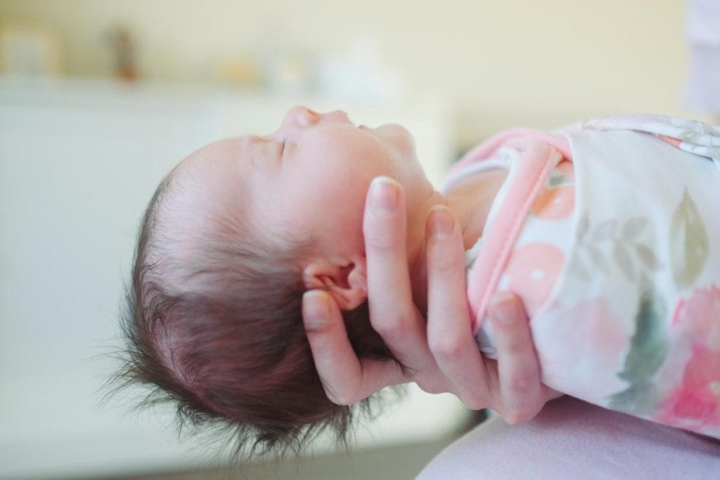 mother's hand holding newborn baby