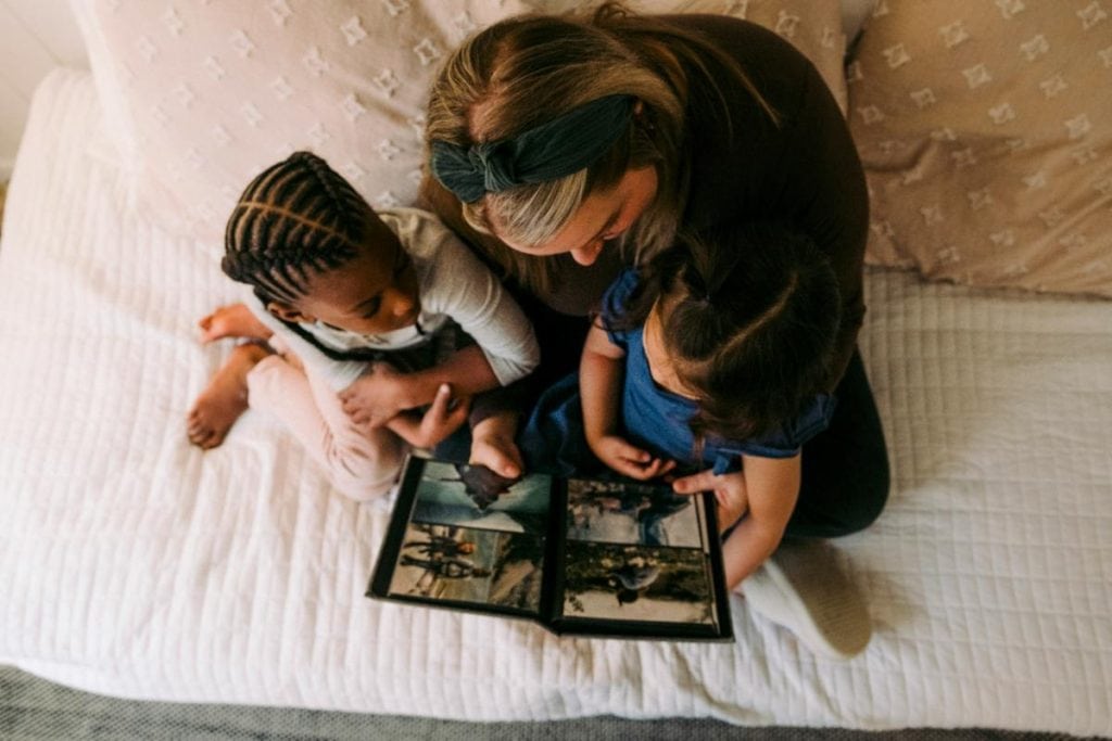 mother and two children sitting on bed and looking at family photos