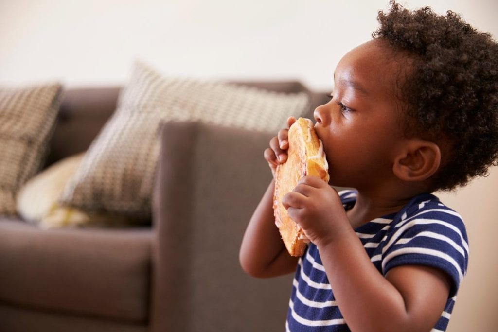 toddler boy with a sandwich in the living room