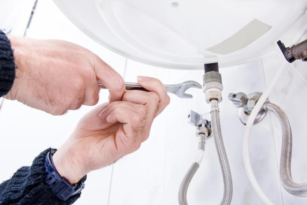 repairman working on a water heater drain