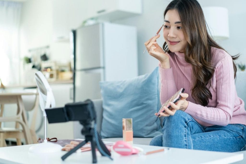 woman applying eyeshadow in front of a camera