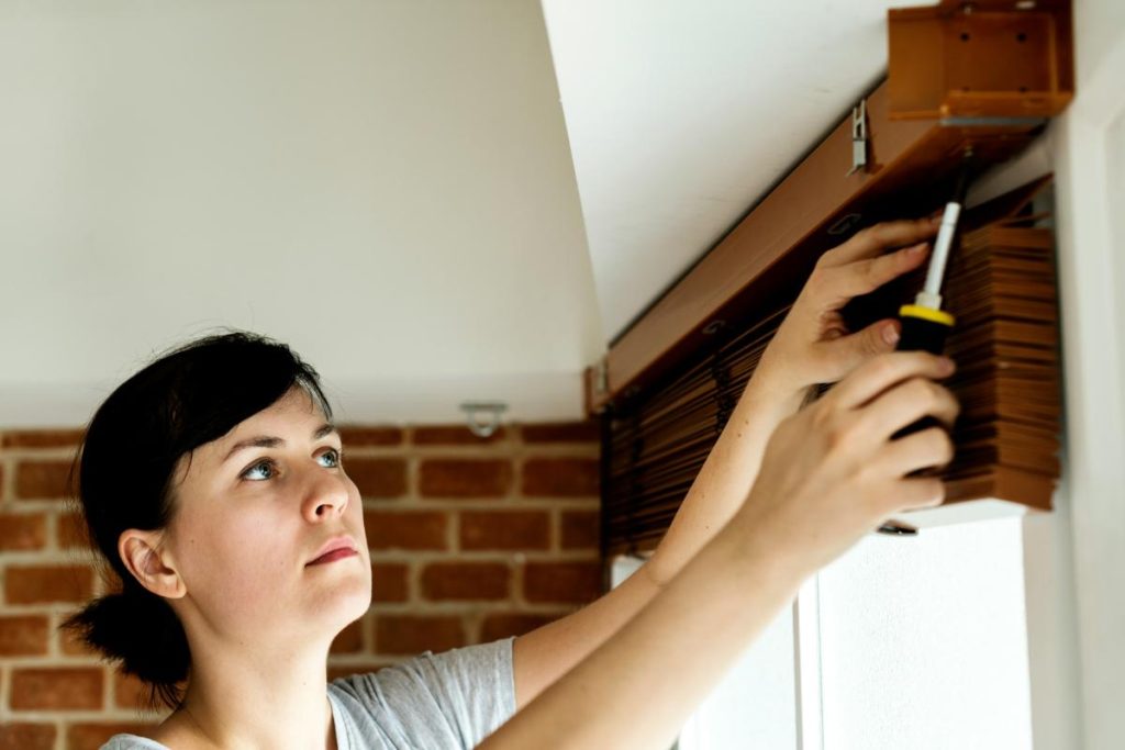 woman installing blinds in window