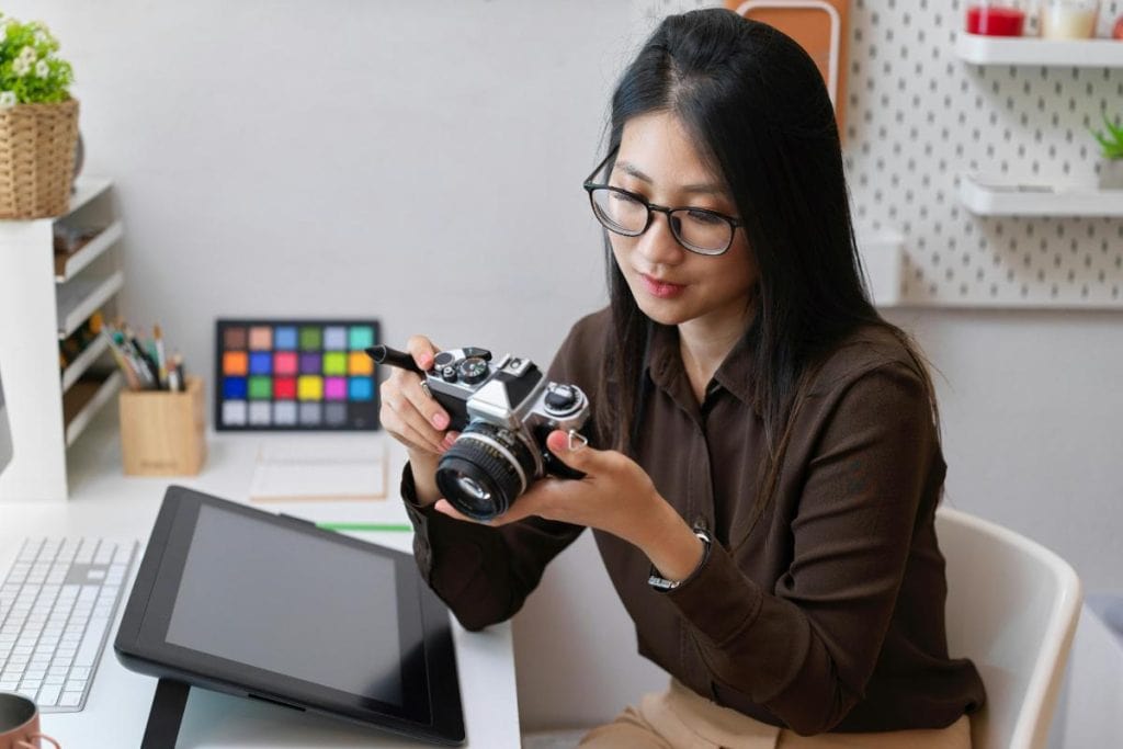 woman editing photos at her desk, looking at the shots on the camera