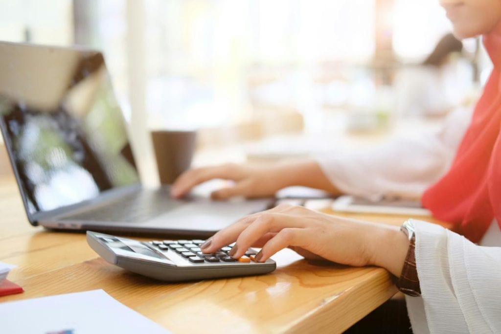 woman using laptop and calculator to work on a budget