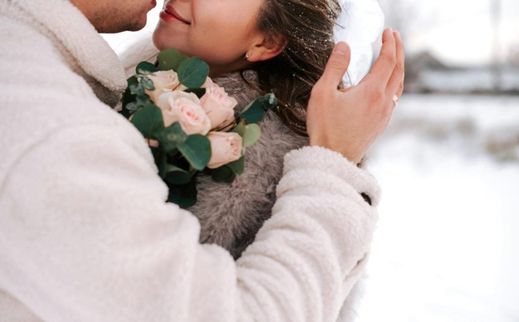 wedding couple embracing in snowy weather