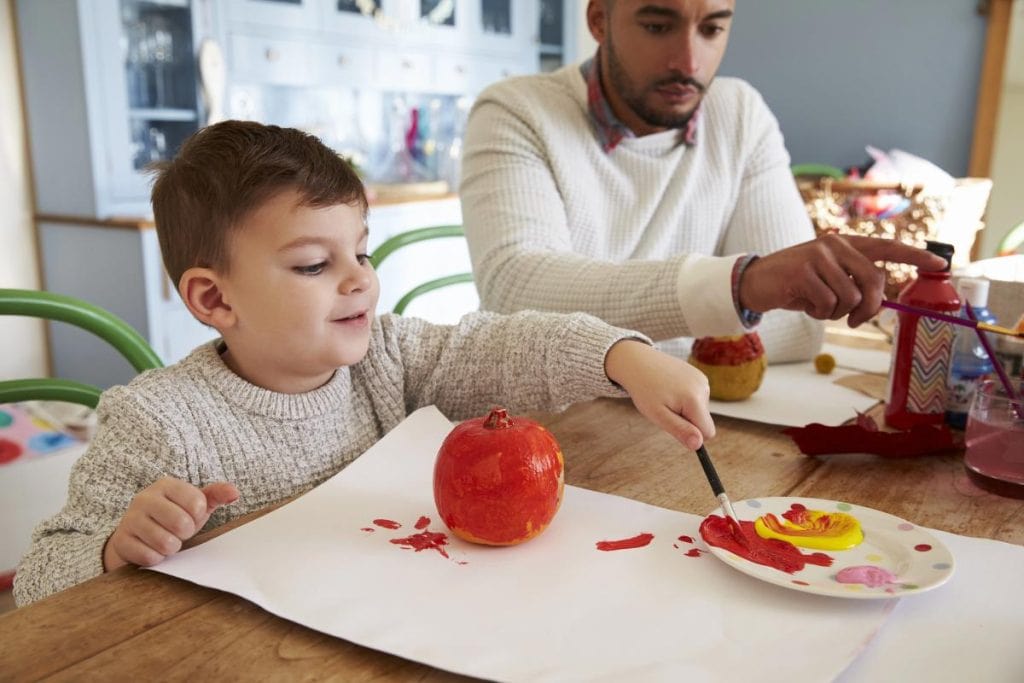 father and son painting small pumpkins