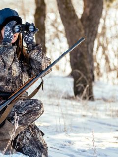 female hunter looking through binoculars