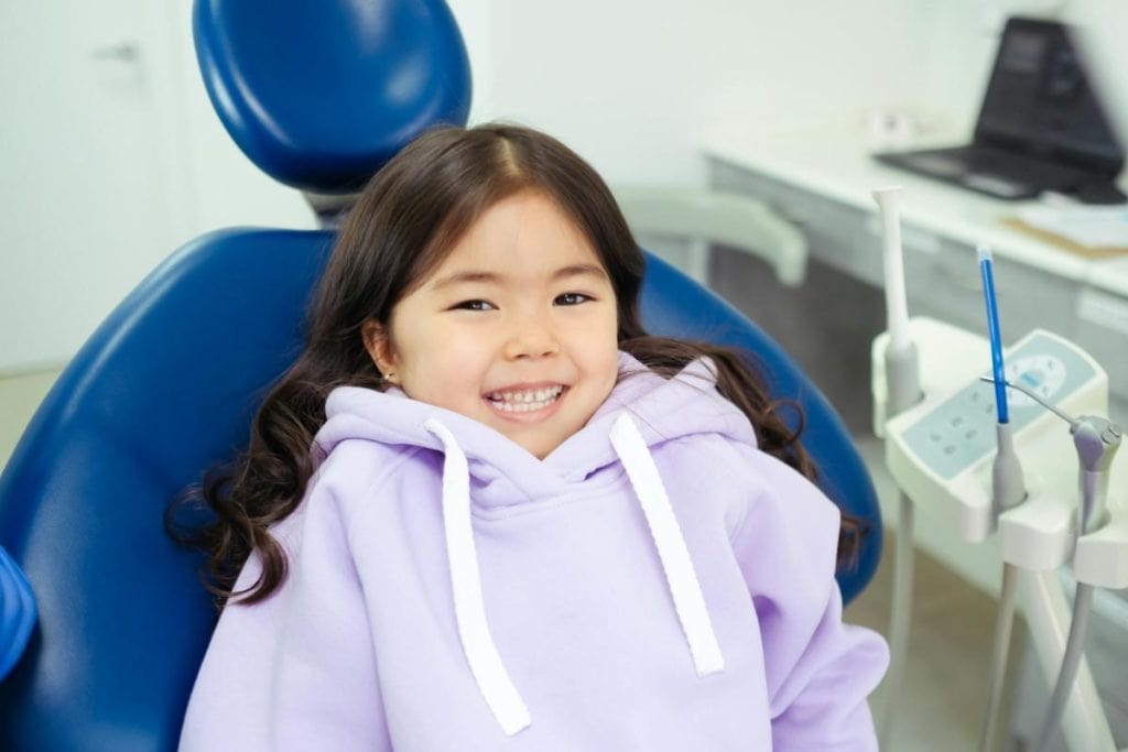 little girl in purple hoodie in dentist's chair