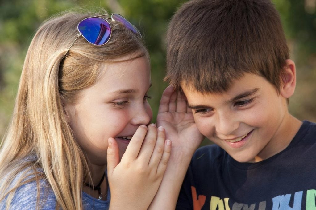 girl whispering to boy