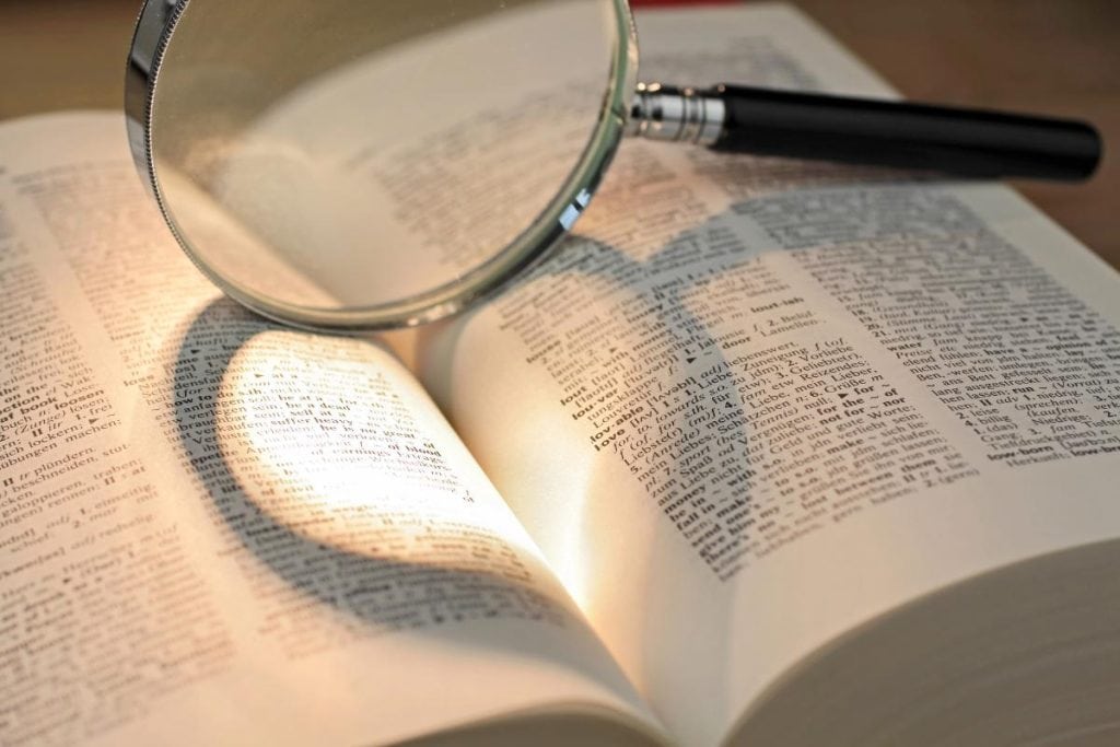 magnifying glass casting a heart shadow on a dictionary