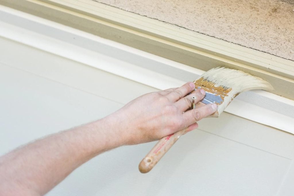 man painting garage door trim