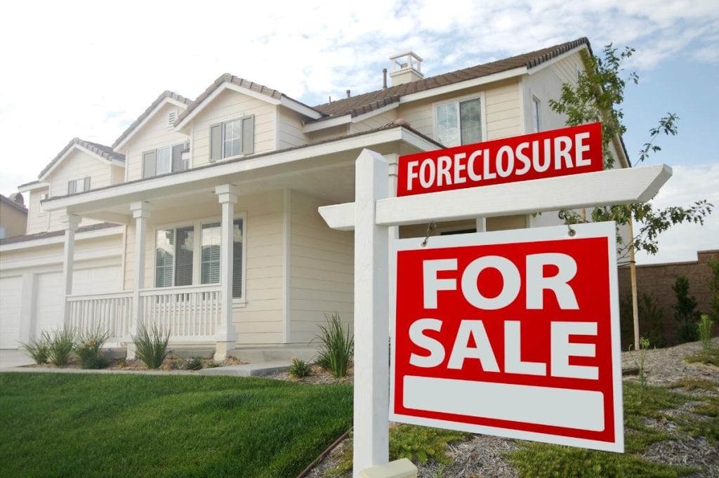 large white house with red foreclosure sign out front