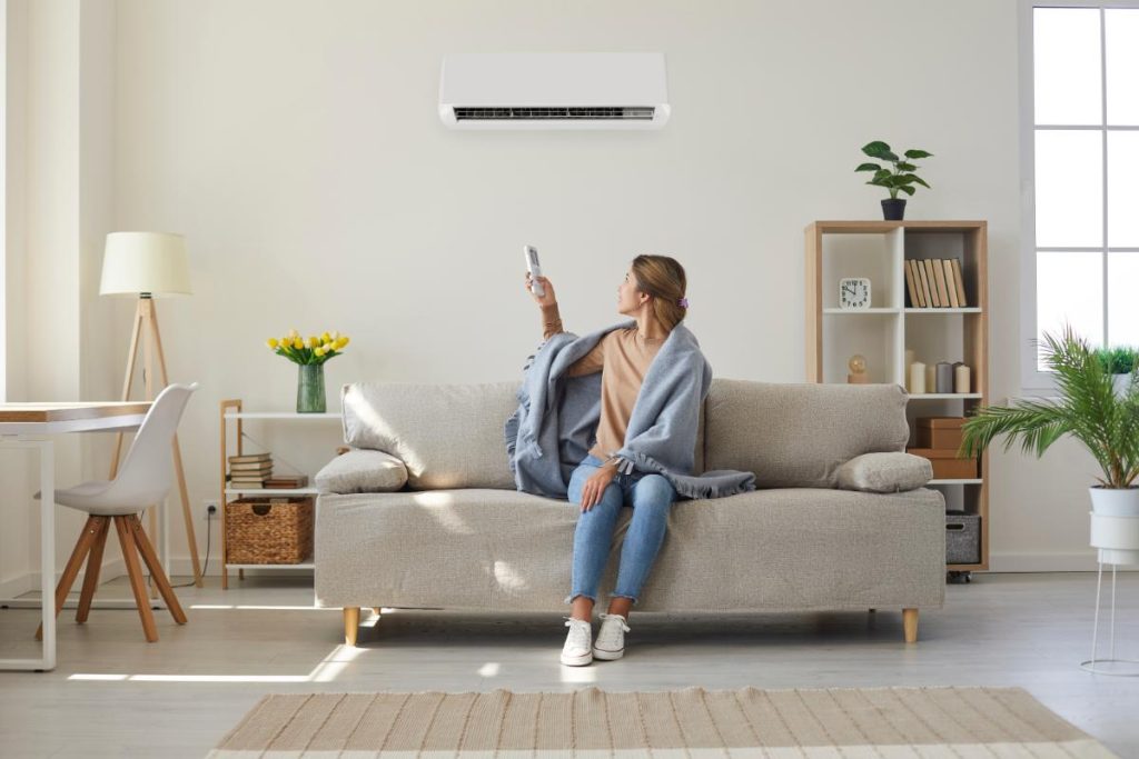 woman with blanket turning on the heat