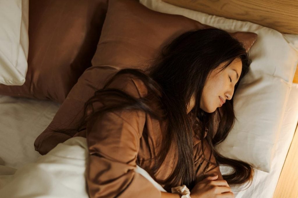 woman resting in a luxurious bed with lots of pillows