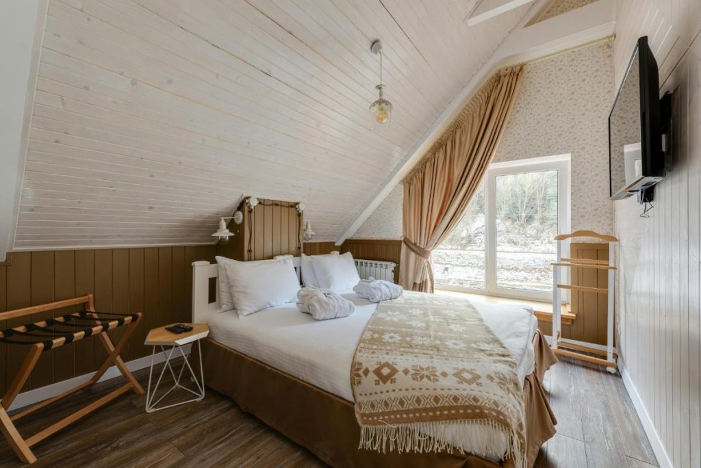 a bedroom with a bed covered in white sheets and beige accent blanket