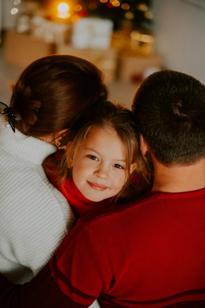 family embracing in front of christmas tree