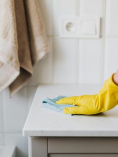 man wearing cleaning gloves wiping down a bathroom sink