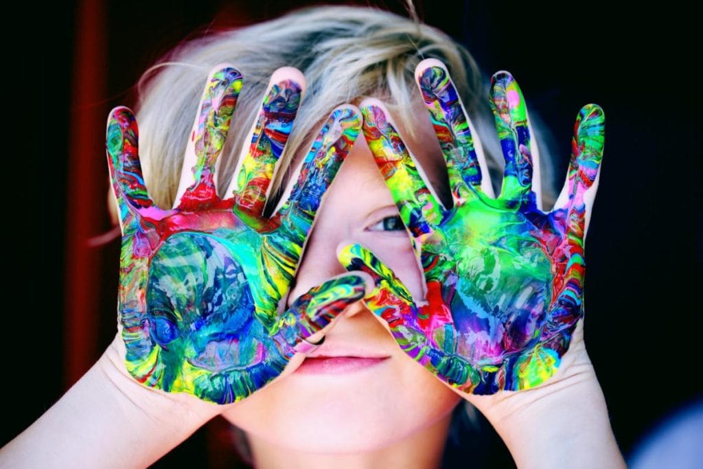 kid with painted palms to make handprint art