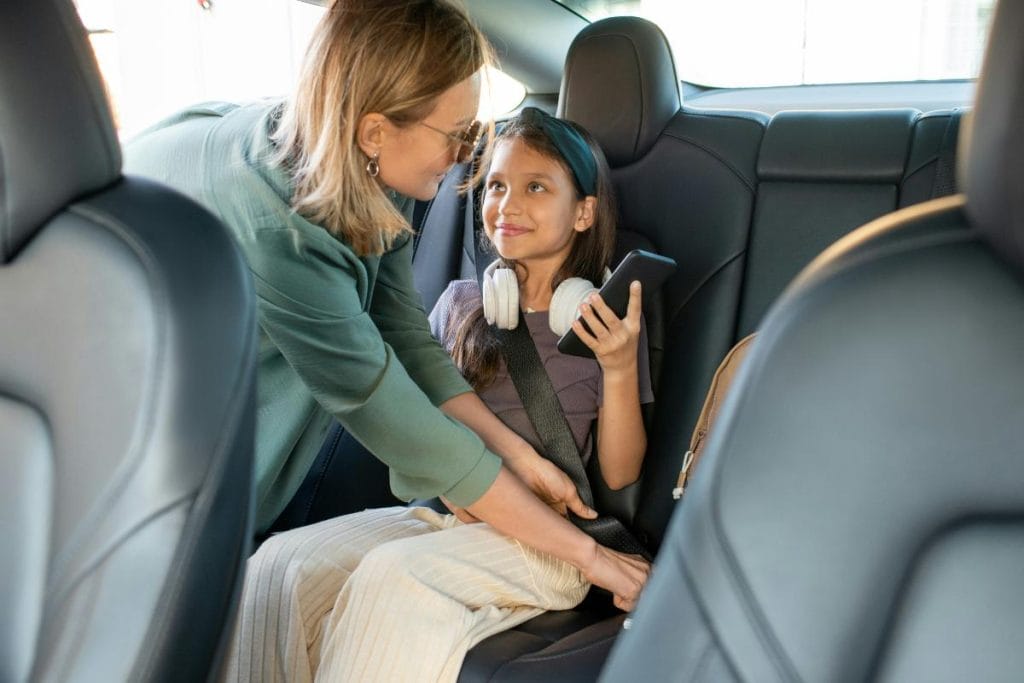 mom buckling her daughter into her seat in the car