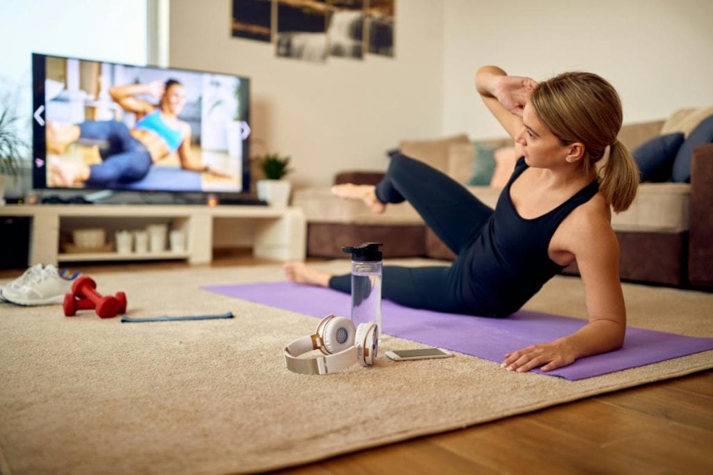 woman exercising in living room floor while watching a video