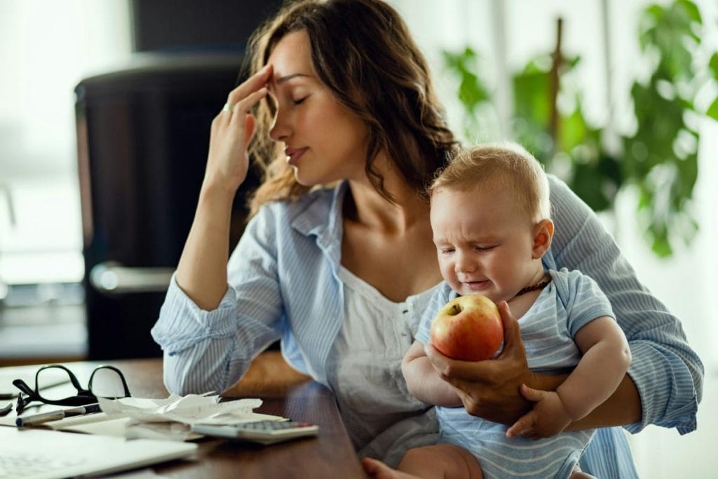 mom with a headache holding her baby