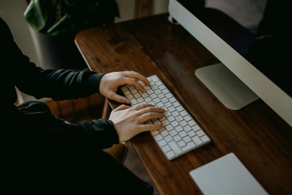 person typing on wireless keyboard at desktop computer