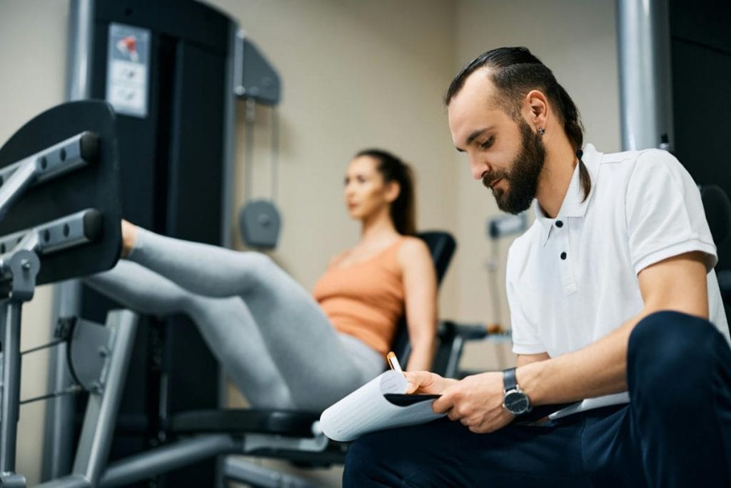 physiotherapist taking notes while patient works out