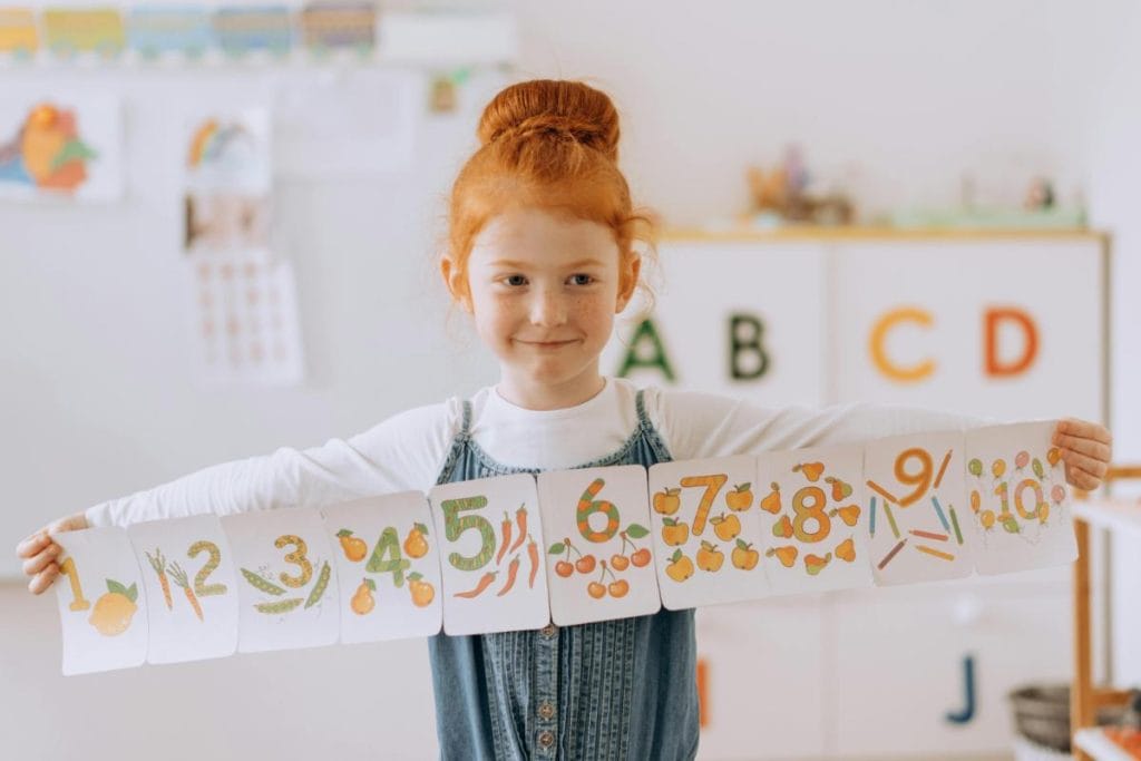 red haired girl holding a number banner for learning to count