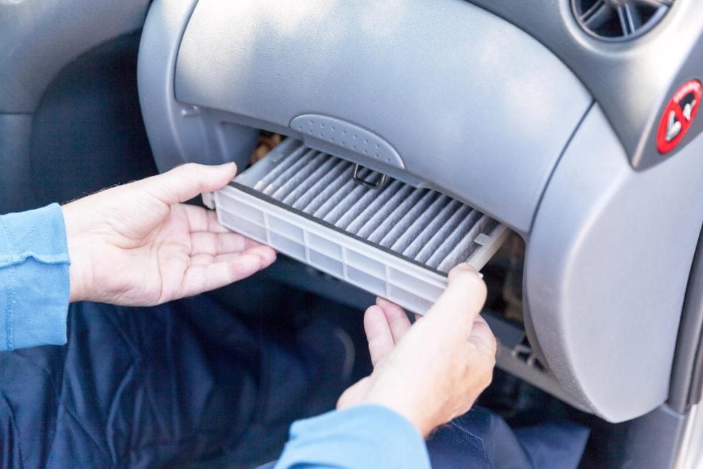 man replacing cabin air filter in car