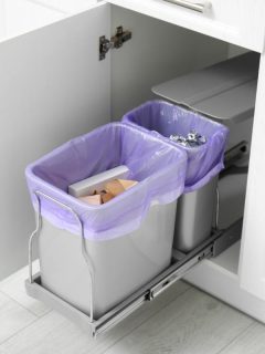 trash bins lined with purple bags in a cabinet