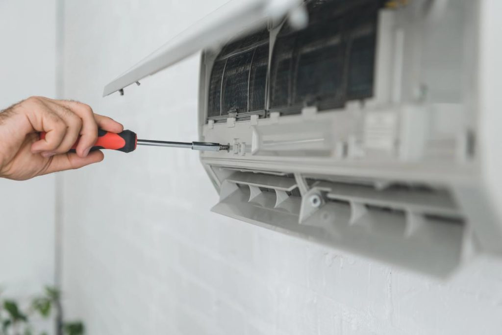 man using a screwdriver on air conditioner unit