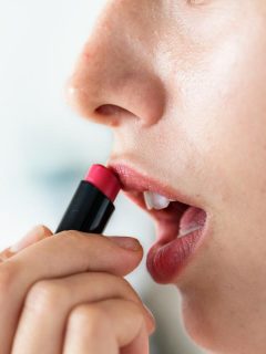 woman applying pink lipstick