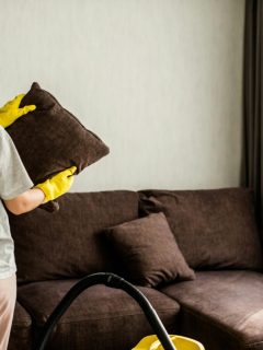 a woman cleaning a brown upholstered couch