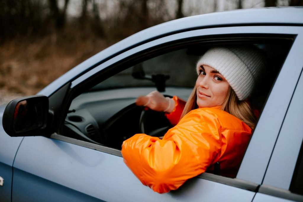 woman in orange coat in car driving