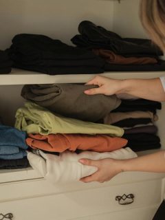 woman putting clothes away on shelf in her closet