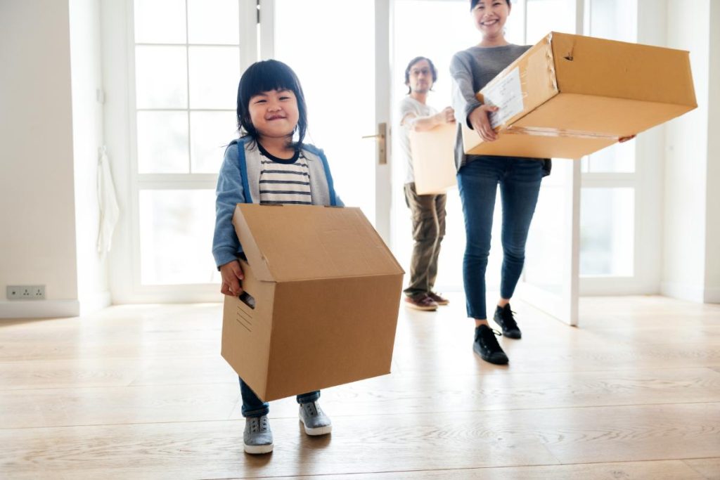 family carrying moving boxes inside