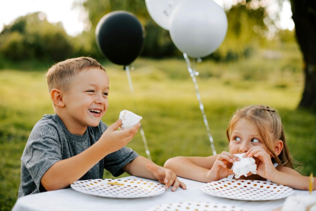 a little boy and girl eating cake at a party