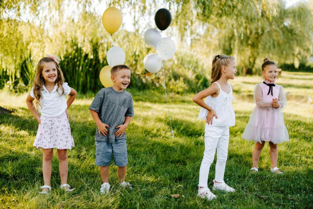 4 little kids (3 girls and 1 boy) smiling and laughing at a party