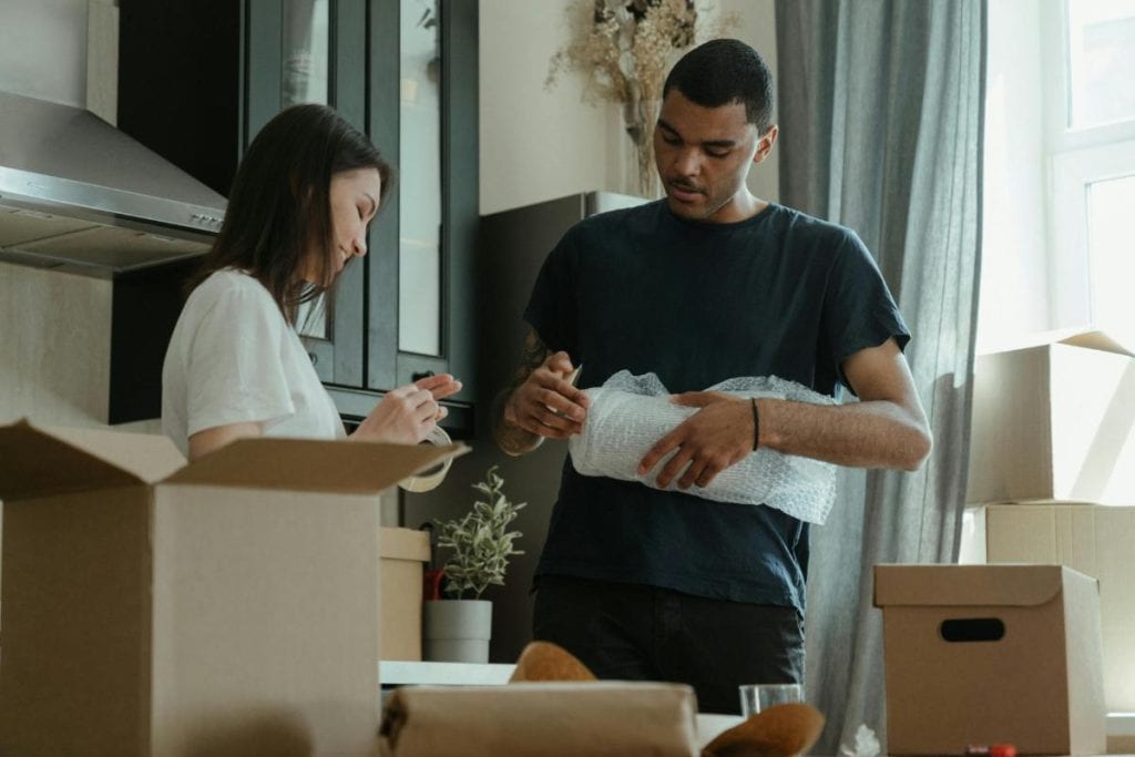 man and woman wrapping items for a move