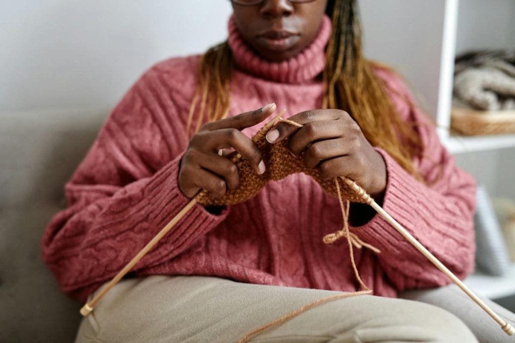 woman in pink sweater knitting