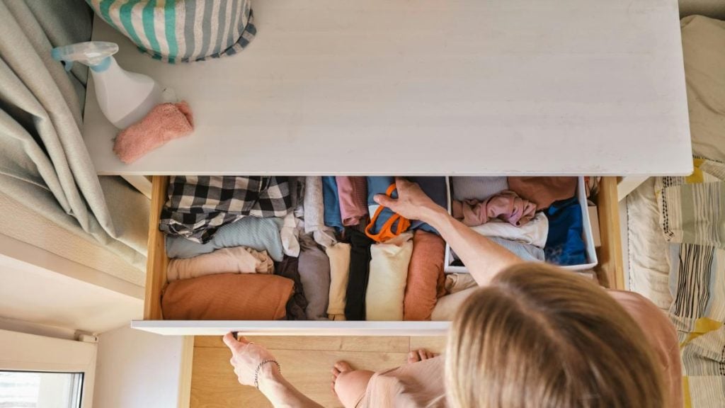 woman putting clothes in a drawer and organizing them