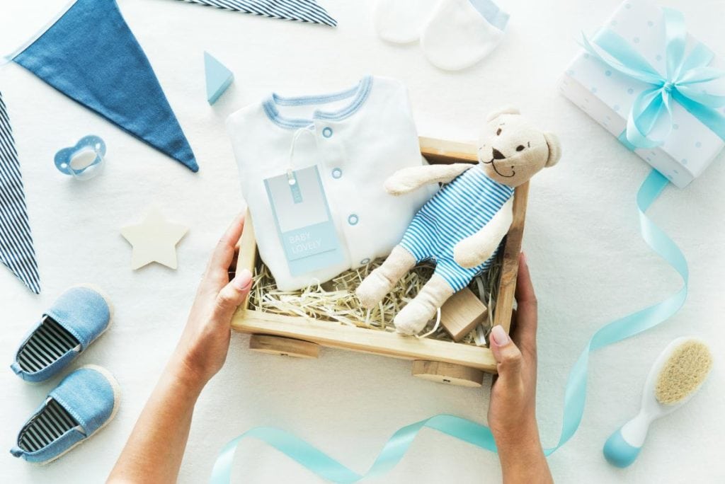 teddy bear and onesie in a basket for a baby boy